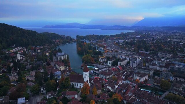Thun Castle Flusswelle Aare River aerial drone view Schloss Thun Thunersee Switzerland Schweiz Europe Autumn Fall morning grey skies buildings yellow birches tree Bernese Oberland backwards pan up