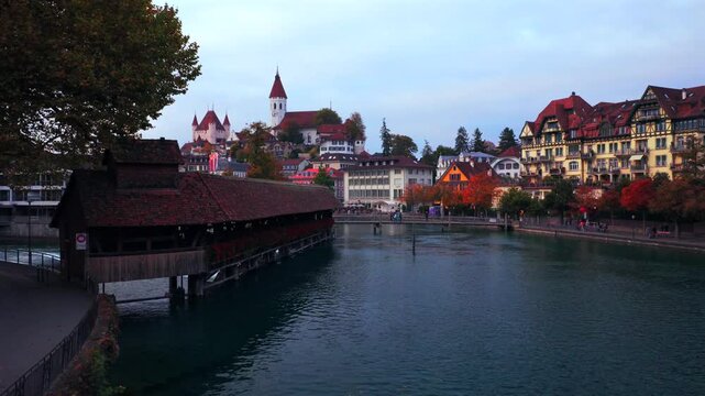 Thun Castle Flusswelle Aare River Schloss Thun Thunersee Switzerland Schweiz Europe Autumn Fall aerial drone view morning grey skies yellow birches tree pedestrian walkway Bernese Oberland upwards