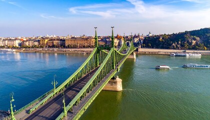 Obraz premium Green Suspension Bridge over River with Cityscape