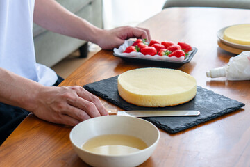 出来合いのスポンジを使ってショートケーキを作る男性
