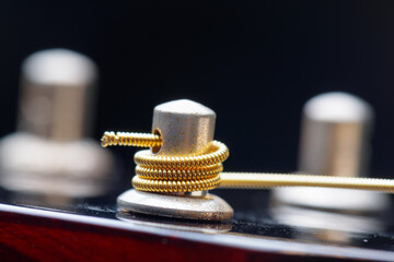 Closeup view of winded new string onto a guitar tuner