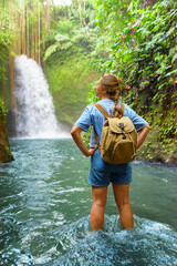 Female tourist with backpack enjoying view of awesome waterfall