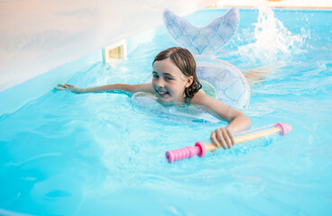 Happy child swimming in a pool with a safety ring on a bright summer day.