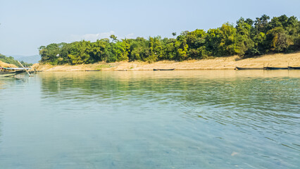 Tranquil River Shore With Greenery and Boats Reflections on Calm Water