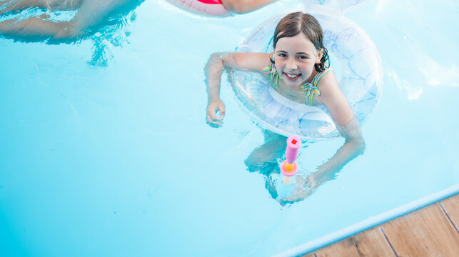 Happy children swimming in a pool with a safety ring on a bright summer day.