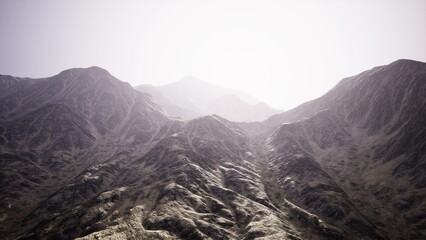 Obraz premium Rugged mountain slopes rise dramatically under a soft, glowing light. The landscape is defined by sharp ridges and textured terrain, inviting exploration and wonder.