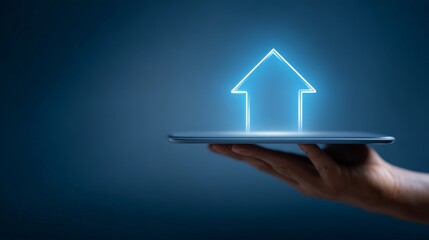 Hand holding a tablet displaying a glowing blue arrow pointing upwards, symbolizing financial growth, business progress, technological innovation, and future development on a dark blue background