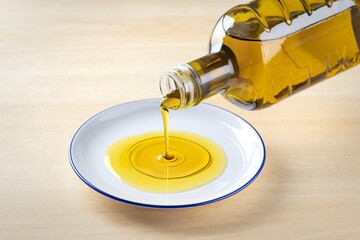A photo of vegetable oil pouring from a clear bottle