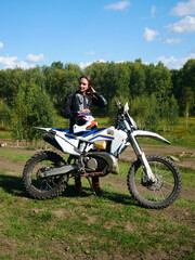Obraz premium Woman off-road biker posing next to her motocross motorcycle. Adventure sport and extreme activity concept for active lifestyle.
