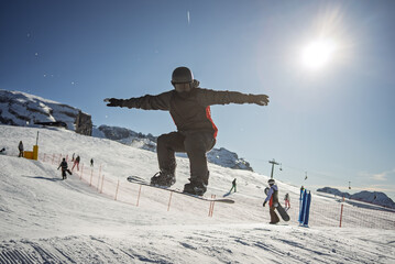 Snowboarder performing air tricks and grab jump in high alpine mountains on sunny winter day. Snowboard grab in the winter mountains. Dolomites, Italy