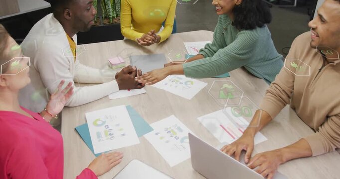 Team sliding chart toward center, stacking hands over charts and laptop signaling business teamwork