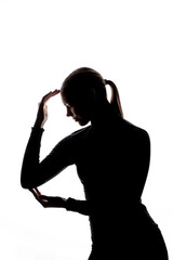 A backlit silhouette of a woman with her hands forming a frame around her face, against a white background with copy space. No visible logos or trademarks