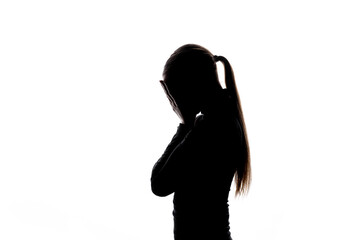 A silhouette of a woman with a ponytail covering her face with both hands, suggesting sadness or anxiety. Isolated on white with copy space. No logos or trademarks visible