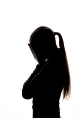 A silhouette of a woman with a ponytail covering her face with both hands, suggesting sadness or anxiety. Isolated on white with copy space. No logos or trademarks visible