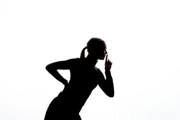 Side-profile silhouette of a woman gesturing "shh" with one finger raised to her lips, set against a bright white background with ample copy space