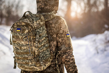 Ukrainian Soldier in Military Uniform with Backpack in Cold Winter in Snow Background with Sunset or Sunrise.