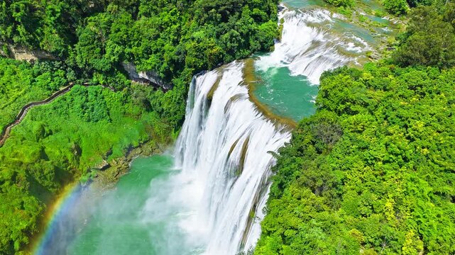 The famous Huangguoshu Waterfall natural landscape in Guizhou, China. Aerial shot of the majestic waterfall cascading into a green lake surrounded by lush forest in summer.