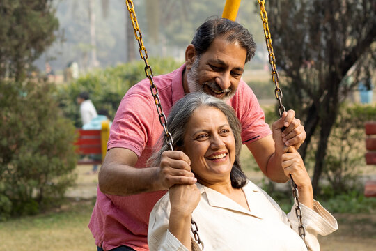 Happy indian old couple swinging at park