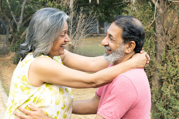 Indian Senior happy couple enjoying in park. Elderly couple embracing, spending time and having fun in vacation time. Senior citizens care hugging or date at the park for romance after retirement. Sen © Pix4Ads