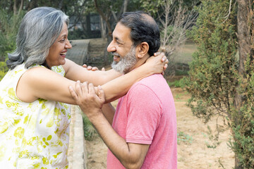 Indian Senior happy couple enjoying in park. Elderly couple embracing, spending time and having fun in vacation time. Senior citizens care hugging or date at the park for romance after retirement. Sen © Pix4Ads