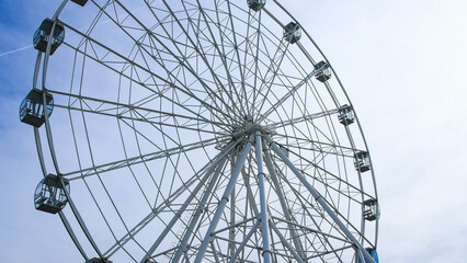 A majestic Ferris wheel stands tall against a clear blue summer sky