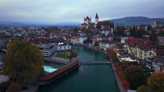 Flusswelle Aare River Schloss Thun sunrise sunset Thun Castle Thunersee Switzerland Schweiz Europe Autumn Fall aerial drone morning grey skies pedestrian walkway car Bernese Oberland backwards motion