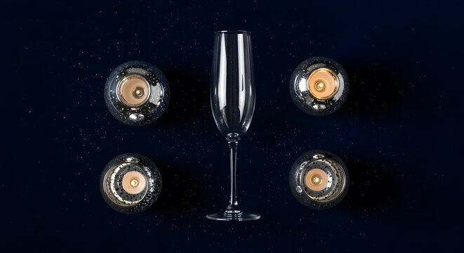 Empty champagne flute centered among four lit mercury glass cand