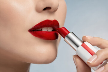 Close-up of a woman applying vibrant red lipstick to her full lips