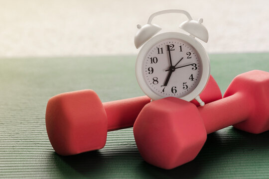 Alarm clock, yoga mat and dumbbells. Morning physical jerks, fitness concept