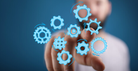 Close-up of a person's hand interacting with a virtual interface of digital gears, symbolizing teamwork, innovation, and business processes.