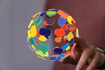 Concept of global communications shown by hand touching colorful speech bubbles. Connection, networking and communication are represented.