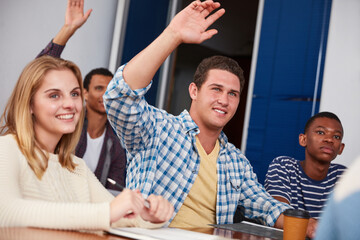 Man, raised hands and question in university class for feedback, knowledge or opinion. Students, communication and gesture for answer with college, learning and pupil in lecture or scholarship