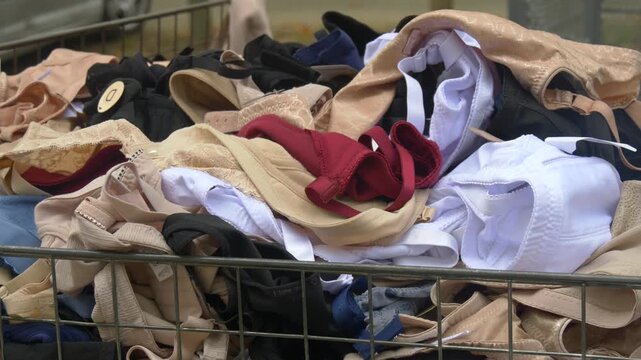 Pile of Women Bras and Underwear in Various Colors Displayed in a Metal Basket at Market