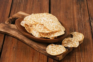 Traditional Indonesian tempe chips served on wooden table, crispy plant based snack concept.