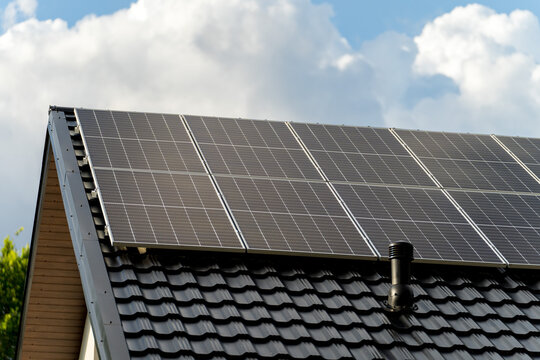 Solar photovoltaic panels mounted on a single family house roof, renewable energy concept for residential electricity production. Clean energy, sustainability and modern home infrastructure.
