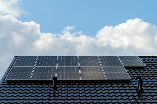 Solar photovoltaic panels mounted on a single family house roof, renewable energy concept for residential electricity production. Clean energy, sustainability and modern home infrastructure.
