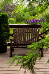 A brown wooden bench next to a pond in a summer park