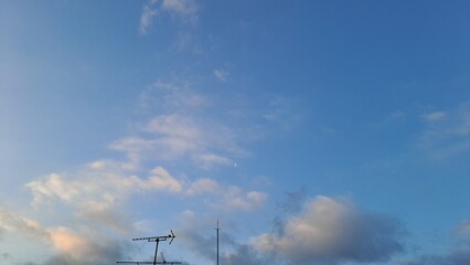 blue sky with crescent moon and airplane contrail