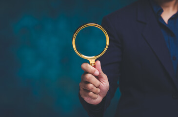 Hand holding magnifying glass for investigation and analysis.