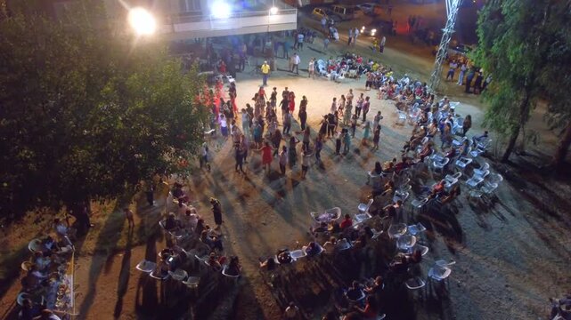 Traditional halay ring performance fills village square during Nowruz wedding celebration night. Community forms circle folk movement creating joyful ethnic festival atmosphere.