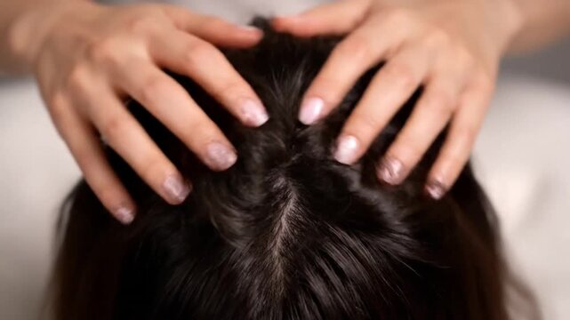 Close Up of Hands Massaging a Woman's Scalp for Hair Care Treatment in a Bright Studio Setting for Product Promotion