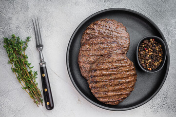Fried mixed meat patties for burgers made from beef and lamb in skillet with herbs. Light stone background with copy space for menu design.