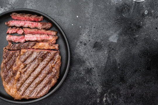 Fried rib eye steak entrecote style sliced medium rare. Grilled beef with rich marbling in plate with rosemary and thyme.