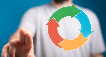 A hand pointing towards a colorful circular arrow diagram, symbolizing business processes, workflow, and concepts like cycle and progress. Ideal