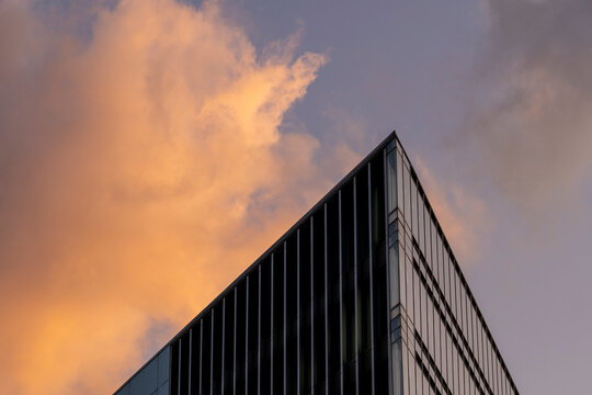 Modern architecture building facade corner with vertical glass lines under sky clouds creating abstract corporate background for business branding