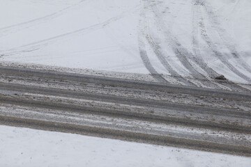 Obraz premium Abstract shot of tire tracks on snowy road surface during winter. Weather conditions, winter drivin