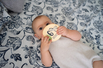 Baby celebrating six months old milestone lying on bed