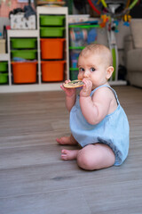 Baby chewing on wooden teething toy in playroom