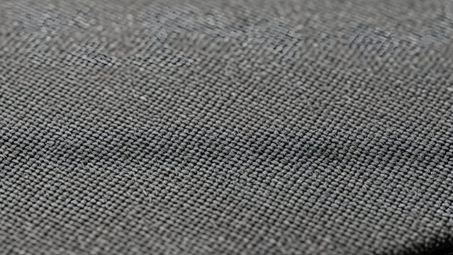 Close-up texture of a gray fabric with a subtle pattern, showcasing its weave and material composition for textile design and fashion concepts
