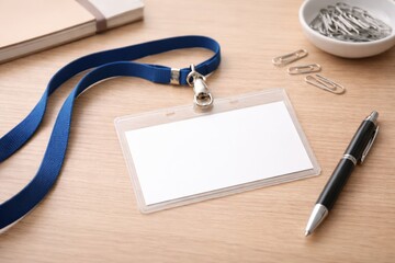 A Blank Name Tag With Lanyard, Paper Clips, and a Pen on a Wooden Desk Surface, Ideal for Personal or Professional Use in Events or Meetings